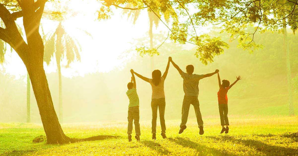 Family jumping holding hands viewed from the back